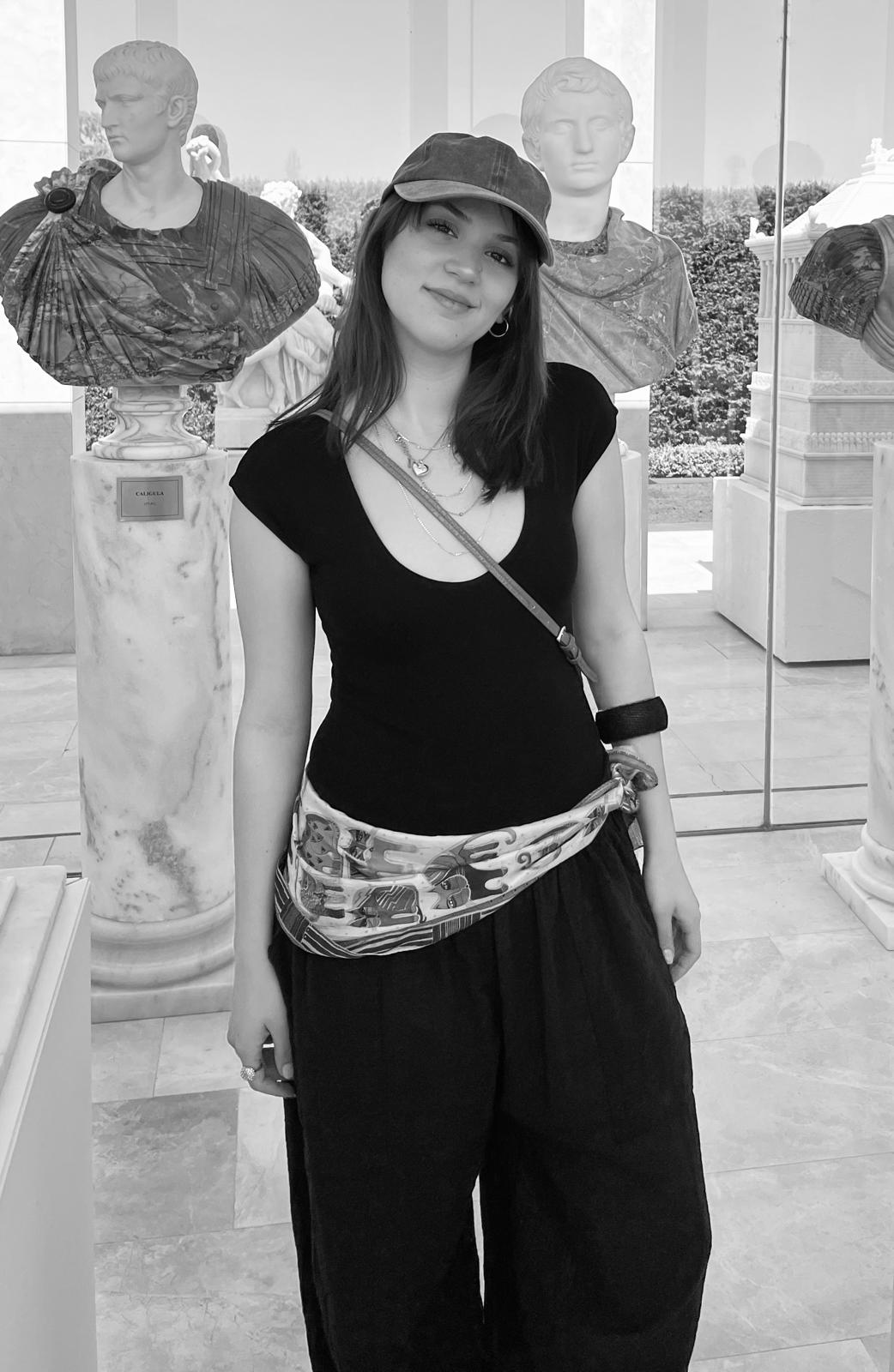 Azra Vardar between classical sculpture busts.